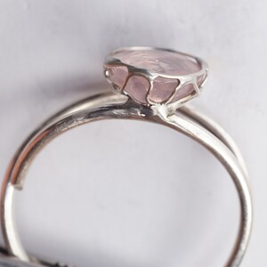 Puede incluir: Un anillo de plata con un delicado engaste en jaula que presenta una piedra de cuarzo rosa p&aacute;lido.