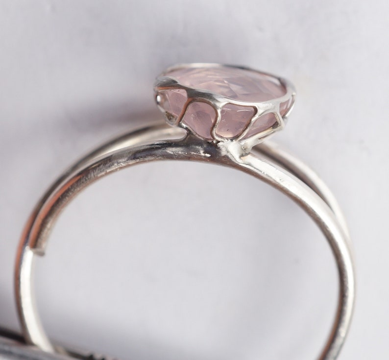 Puede incluir: Un anillo de plata con un delicado engaste en jaula que presenta una piedra de cuarzo rosa p&aacute;lido.