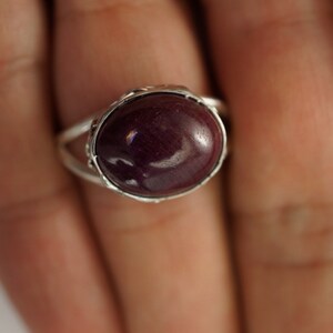Pu&ograve; includere: Un anello d'argento con una grande pietra ovale di colore viola scuro.