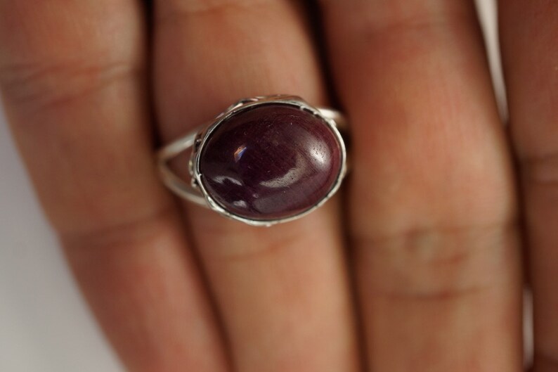 Pu&ograve; includere: Un anello d'argento con una grande pietra ovale di colore viola scuro.