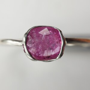 Op de afbeelding: Een zilveren ring met een roze edelsteen gezet in een getextureerde zetting.