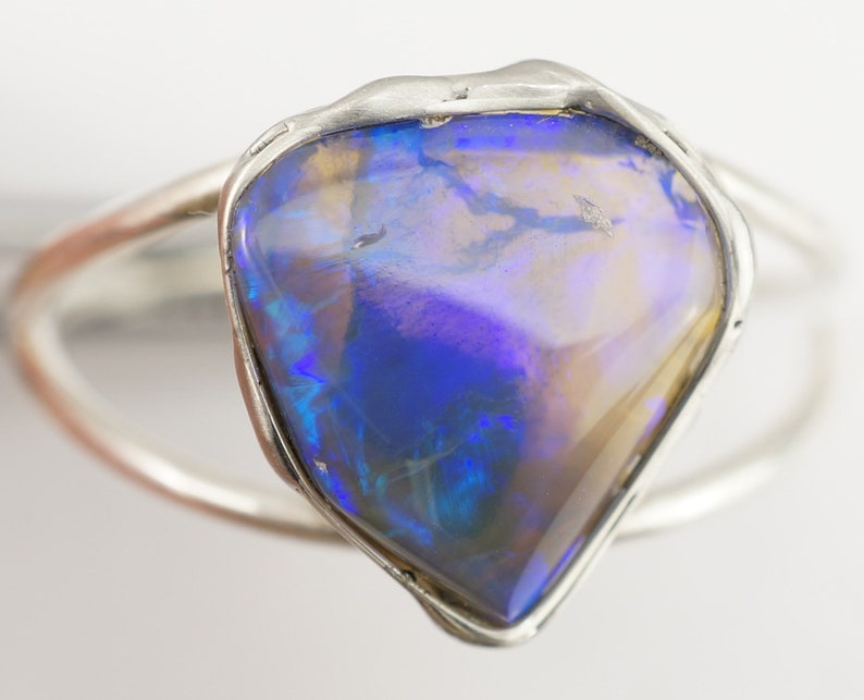 May include: A silver ring with a large, blue, iridescent opal gemstone set in a rough, irregular shape.