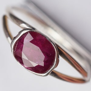 Op de afbeelding: Een zilveren ring met een grote, gefacetteerde robijn. De robijn is diep rood van kleur en is gezet in een bezel setting.