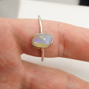 May include: A silver ring with a white opal gemstone set in a textured band.
