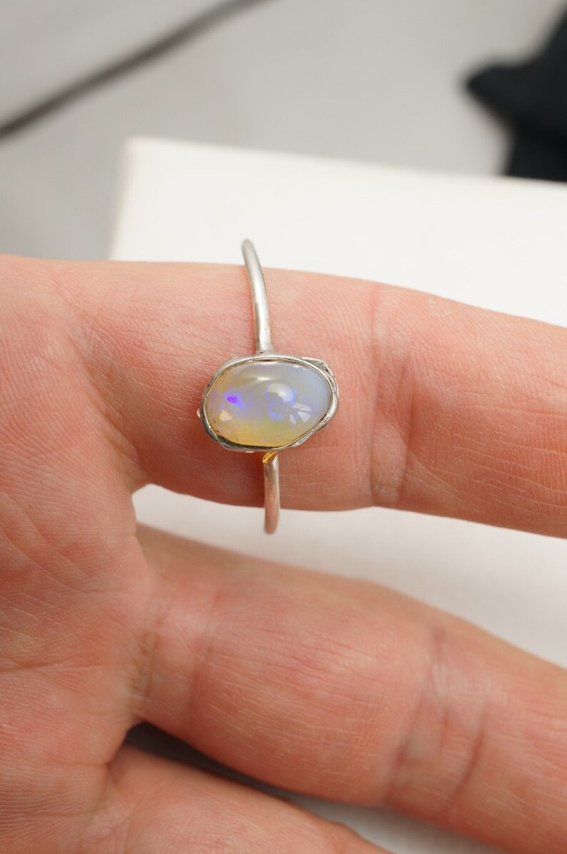 May include: A silver ring with a white opal gemstone set in a textured band.