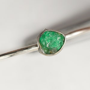 Peut inclure: Une bague en argent avec une grosse &eacute;meraude brute de couleur verte.