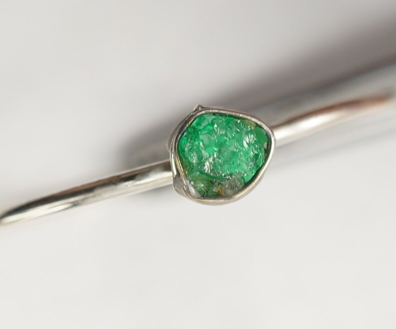 Peut inclure: Une bague en argent avec une grosse &eacute;meraude brute de couleur verte.