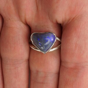 Puede incluir: Un anillo de plata con una piedra preciosa de &oacute;palo azul en forma de coraz&oacute;n.