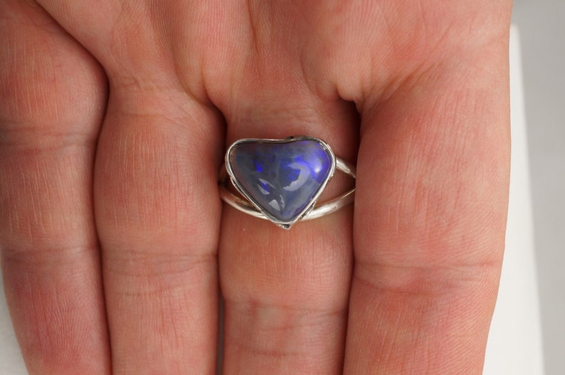 Puede incluir: Un anillo de plata con una piedra preciosa de &oacute;palo azul en forma de coraz&oacute;n.