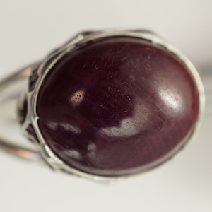 Pu&ograve; includere: Un anello d'argento con una grande pietra preziosa di colore viola scuro incastonata in una montatura decorata.
