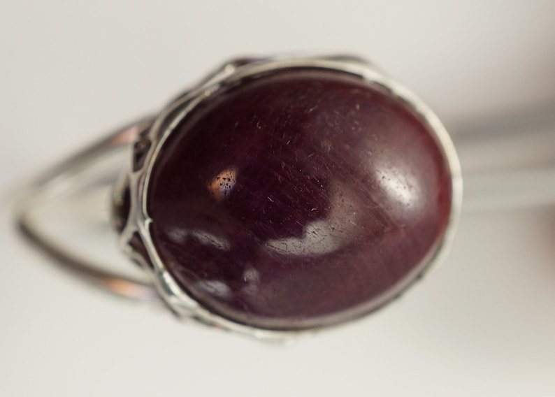 Pu&ograve; includere: Un anello d'argento con una grande pietra preziosa di colore viola scuro incastonata in una montatura decorata.