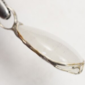 May include: A silver pendant with a clear teardrop-shaped stone set in a delicate silver frame.