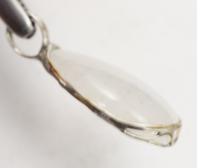 May include: A silver pendant with a clear teardrop-shaped stone set in a delicate silver frame.