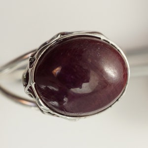 Pu&ograve; includere: Un anello d'argento con una grande pietra ovale di colore rosso scuro.