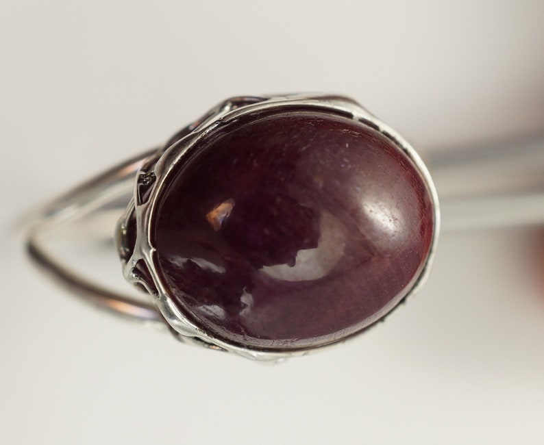 Pu&ograve; includere: Un anello d'argento con una grande pietra ovale di colore rosso scuro.