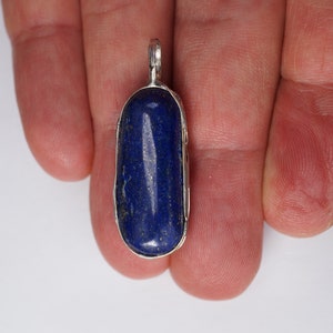 May include: A silver pendant with a deep blue lapis lazuli stone set in a bezel setting.