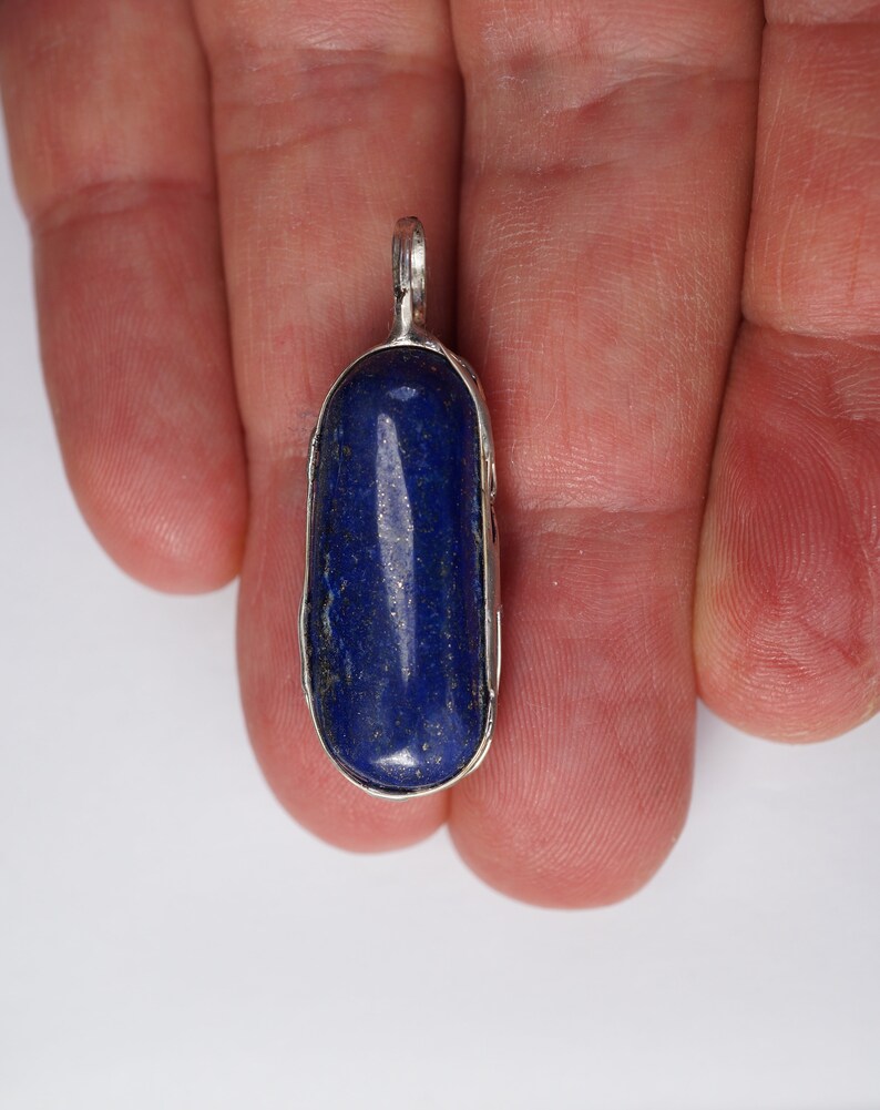 May include: A silver pendant with a deep blue lapis lazuli stone set in a bezel setting.