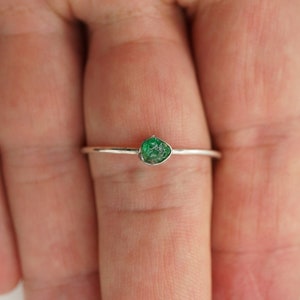 Peut inclure: Une bague en argent avec une petite pierre pr&eacute;cieuse verte sertie au centre.