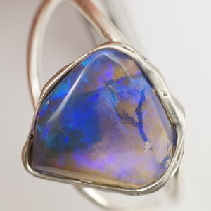 May include: A silver ring with a large, blue opal gemstone. The opal has a unique, iridescent pattern.