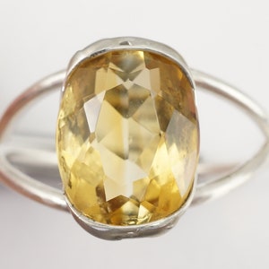May include: A silver ring with a large, faceted, yellow citrine gemstone.