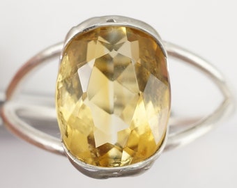 May include: A silver ring with a large, faceted, yellow citrine gemstone.