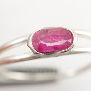 May include: A silver ring with a pink oval-shaped gemstone set in a delicate, textured setting.