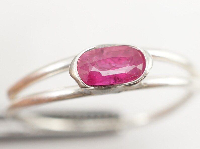 May include: A silver ring with a pink oval-shaped gemstone set in a delicate, textured setting.