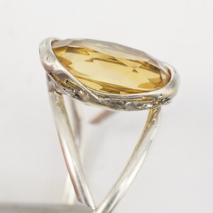 May include: A silver ring with a large, oval-shaped, light brown gemstone set in a twisted silver band.