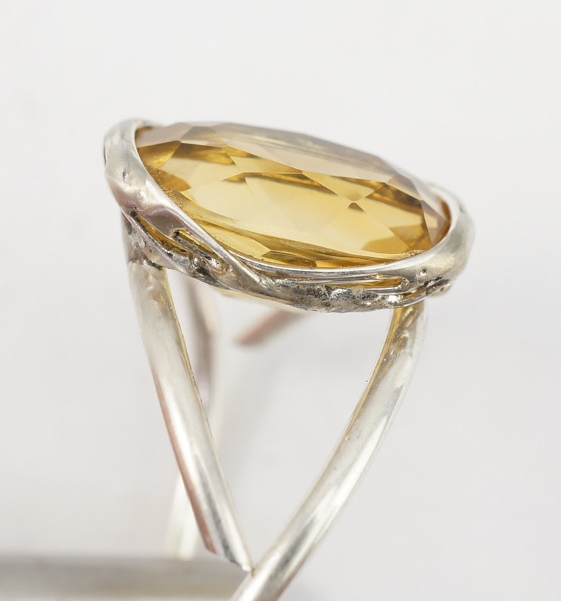 May include: A silver ring with a large, oval-shaped, light brown gemstone set in a twisted silver band.