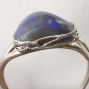 Puede incluir: Un anillo de plata con una piedra de &oacute;palo azul oscuro engastada en un dise&ntilde;o delicado e intrincado.