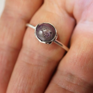 May include: A silver ring with a purple gemstone set in a bezel setting.