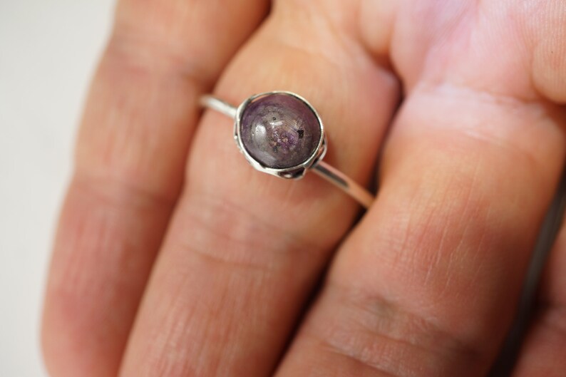 May include: A silver ring with a purple gemstone set in a bezel setting.