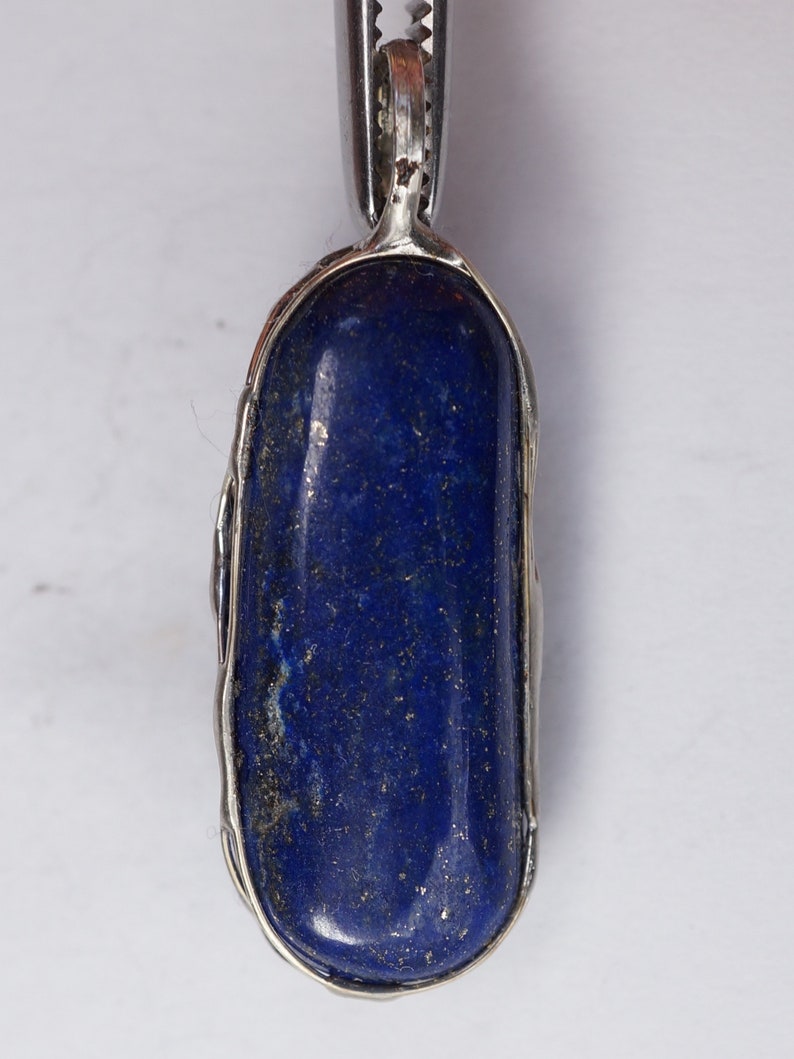 May include: A silver pendant with a deep blue lapis lazuli stone set in a silver bezel.