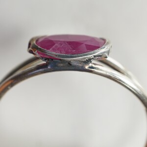 May include: A silver ring with a pink oval-shaped gemstone set in a bezel setting.