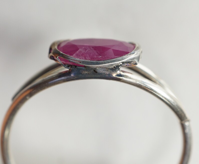 May include: A silver ring with a pink oval-shaped gemstone set in a bezel setting.