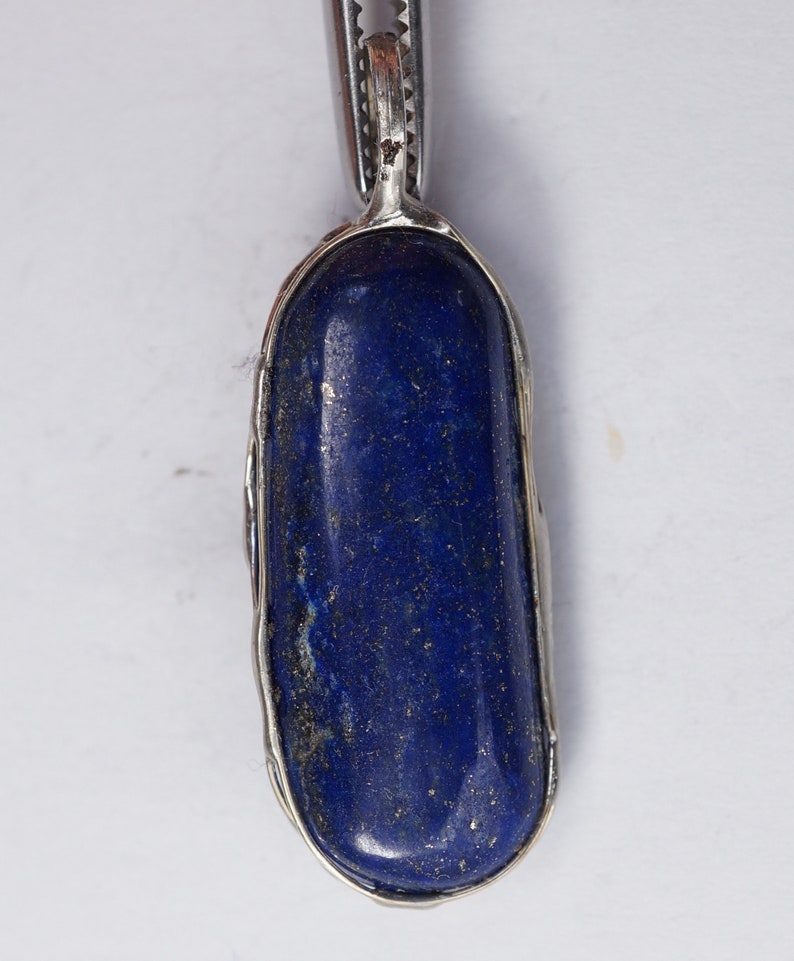 May include: A silver pendant with a deep blue lapis lazuli stone set in a bezel setting.