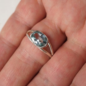 May include: A silver ring with a light blue oval gemstone.