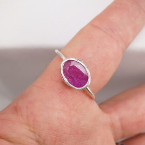 Op de afbeelding: Een zilveren ring met een roze ovale edelsteen in een bezel-setting.