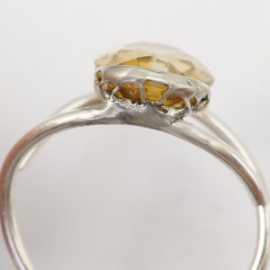 May include: A silver ring with a yellow gemstone set in a delicate, intricate design.