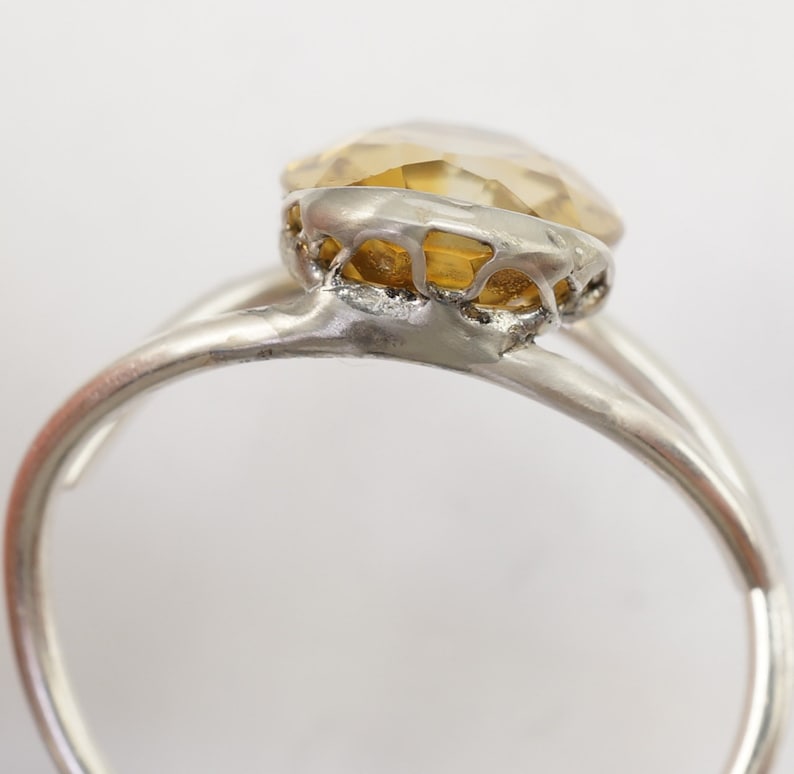 May include: A silver ring with a yellow gemstone set in a delicate, intricate design.