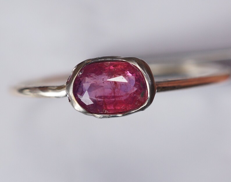 May include: A silver ring with a pink oval gemstone set in a textured bezel.