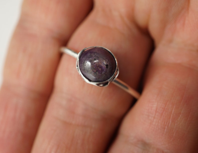 May include: A silver ring with a purple gemstone set in a bezel setting.