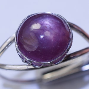 May include: A silver ring with a large, round, purple gemstone set in a silver bezel.