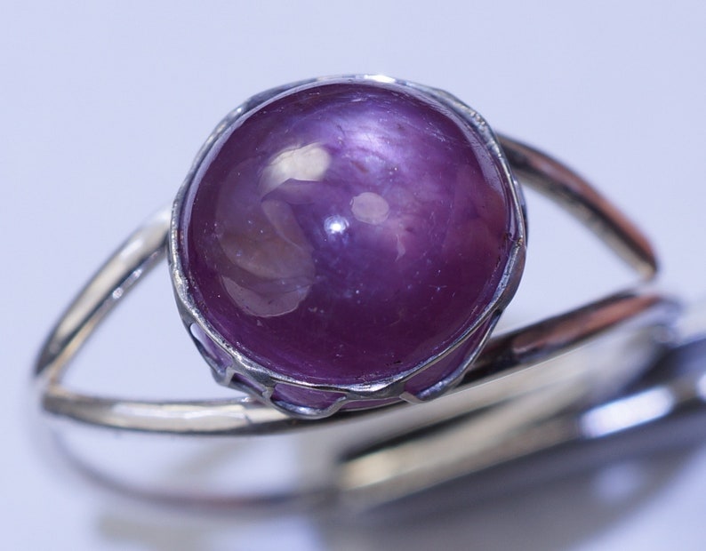 May include: A silver ring with a large, round, purple gemstone set in a silver bezel.