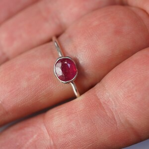 May include: A silver ring with a red oval gemstone.