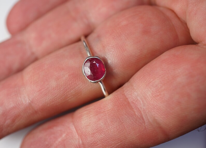 May include: A silver ring with a red oval gemstone.