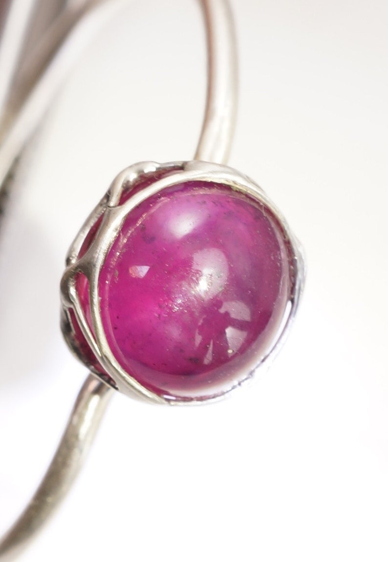 May include: A silver ring with a large, round, cabochon-cut, pink gemstone set in a delicate, wire-wrapped setting.