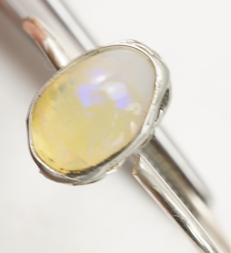 May include: A silver ring with a yellow opal gemstone set in a bezel setting.