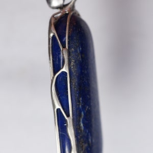May include: A silver pendant with a blue lapis lazuli stone set in a delicate silver frame.