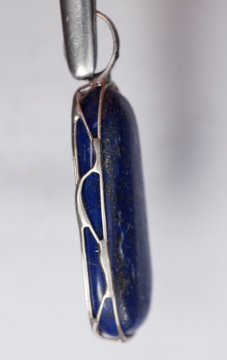 May include: A silver pendant with a blue lapis lazuli stone set in a delicate silver frame.